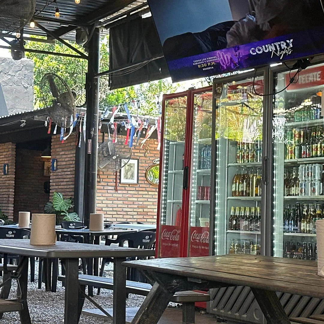 Terraza de la sucursal Diagonal de Mr. Smoky, con mesas de madera y refrigeradores de bebidas