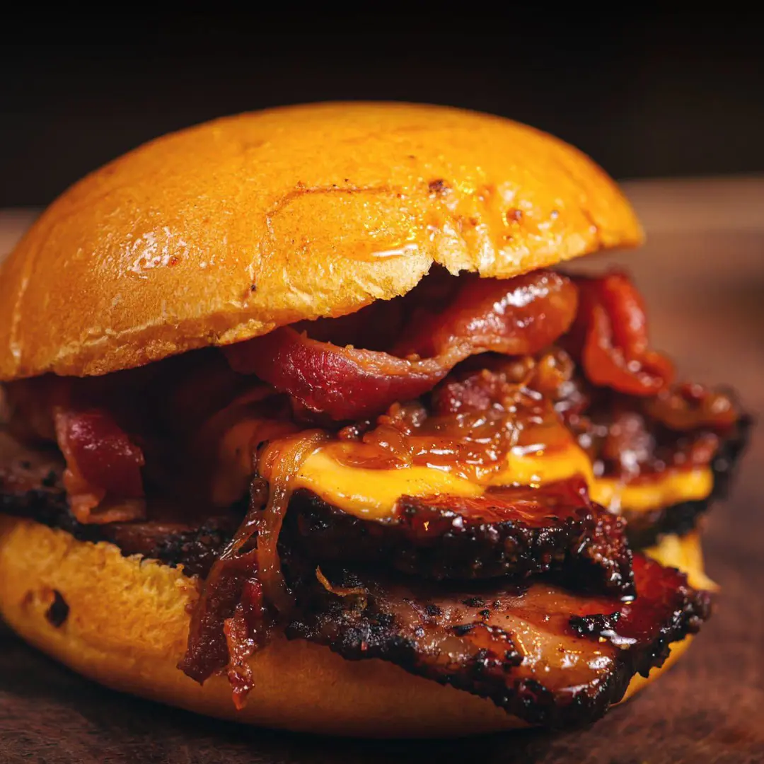 Dirty brisket sándwich con queso fundido y tocino en pan brioche