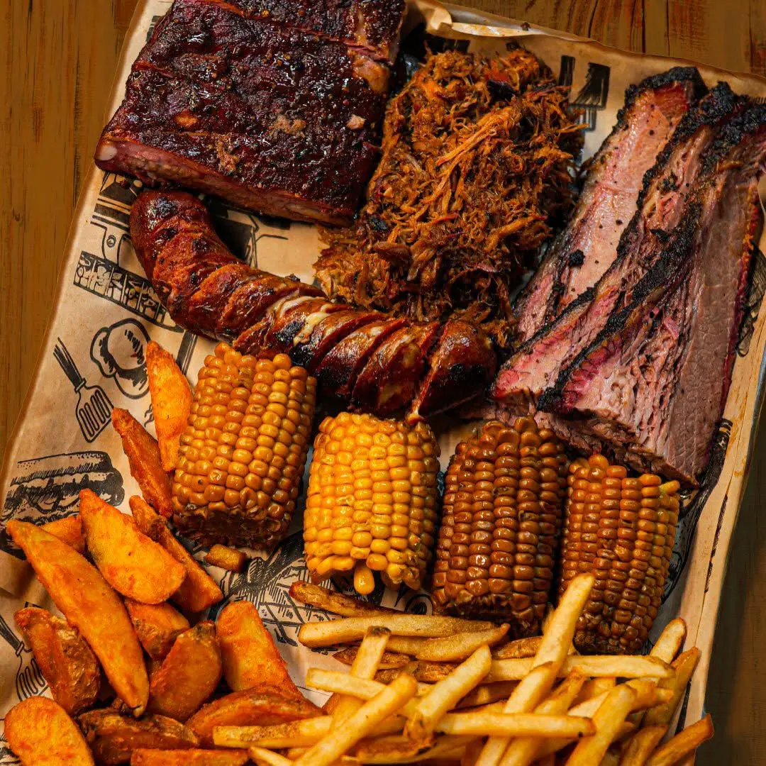 Charola de barbecue con carnes ahumadas, elotes y papas