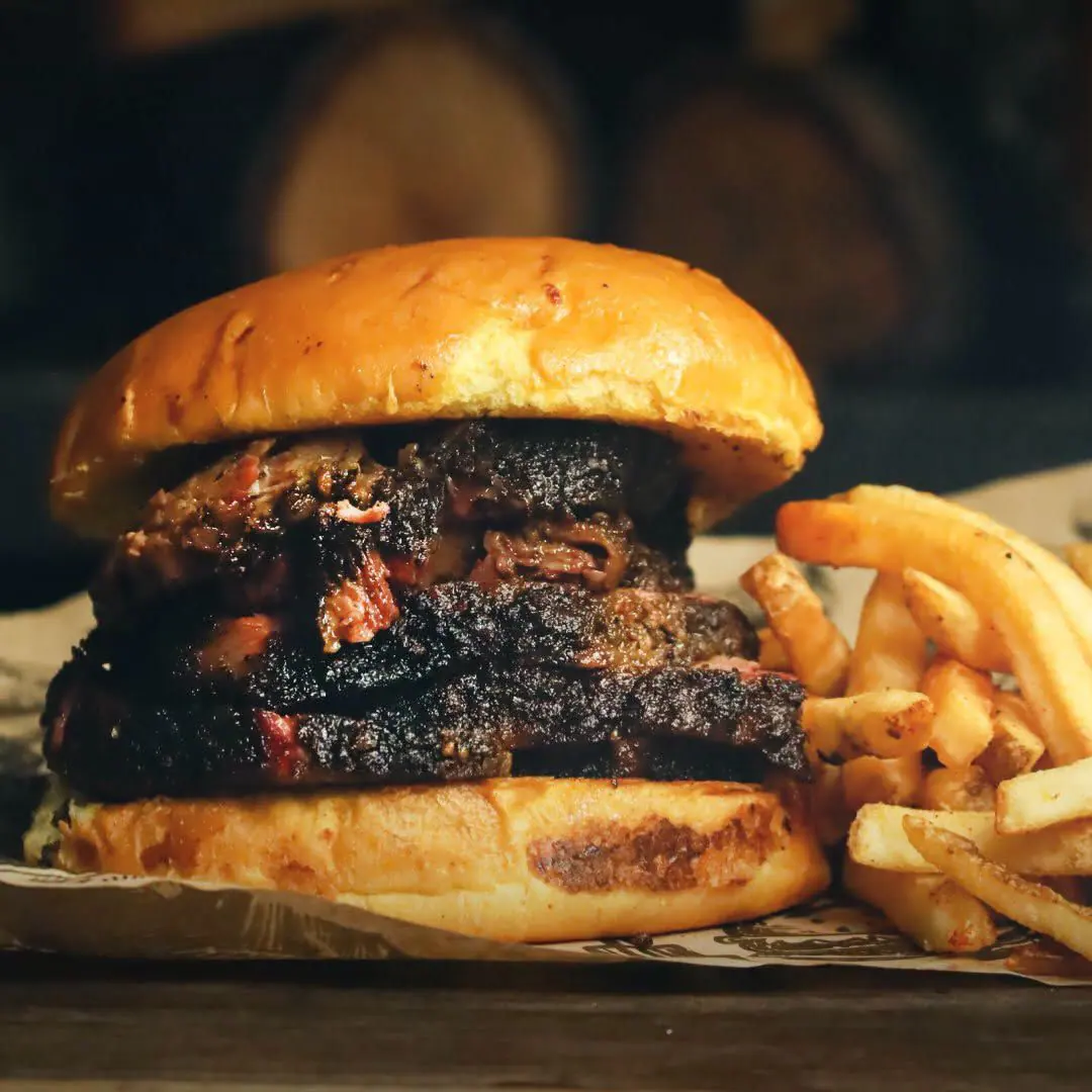 Sándwich de brisket rebanado en brioche, servido con papas